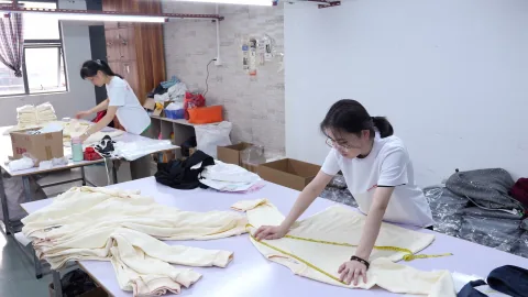 OTO team member measures a light-coloured garment with a tape measure