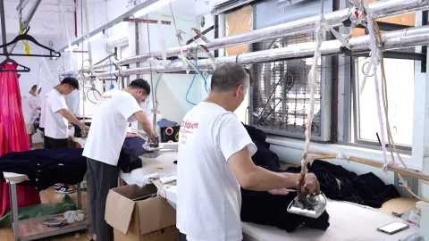 OTO finishing team presses dark garments at ironing stations